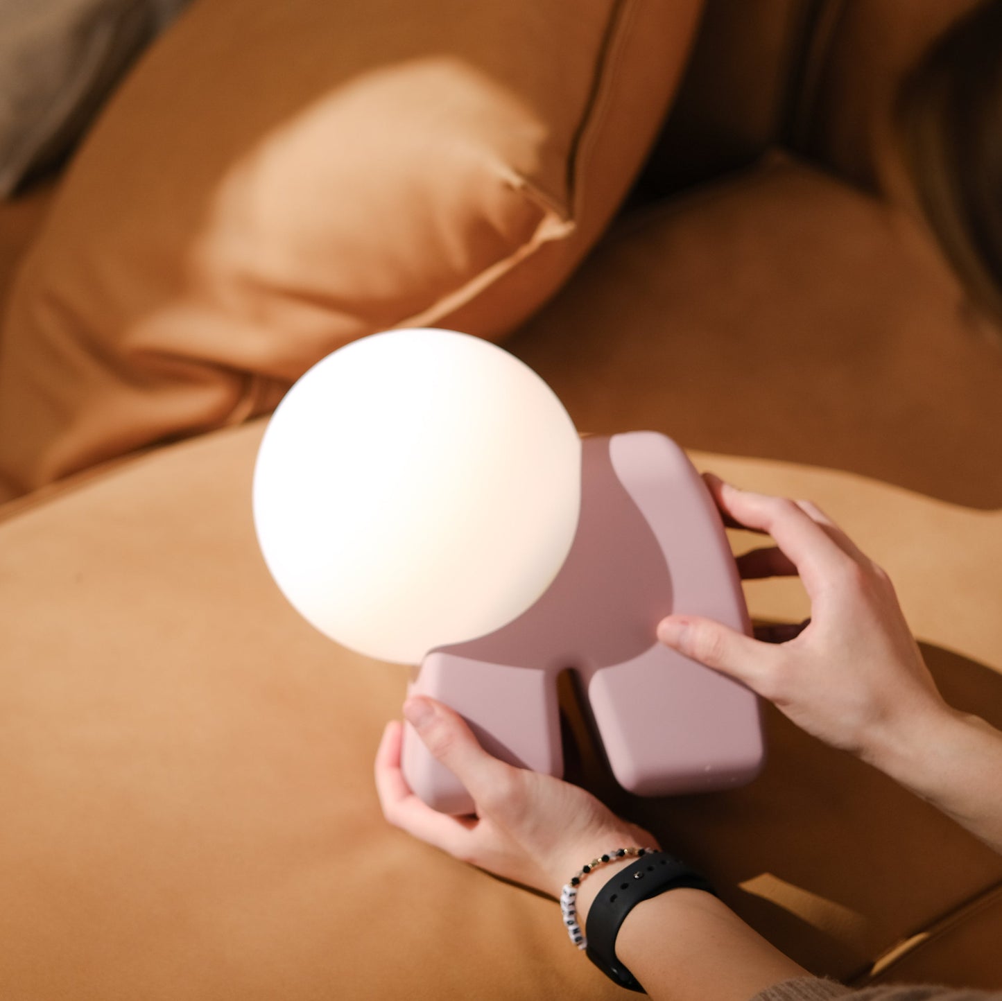 Person holding a small round lamp on a brown couch