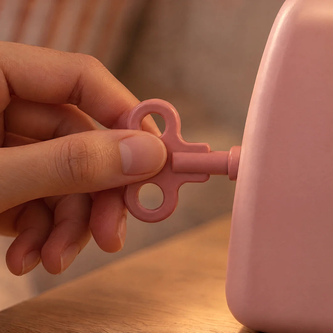 A hand turns Puppy’s pink winding key