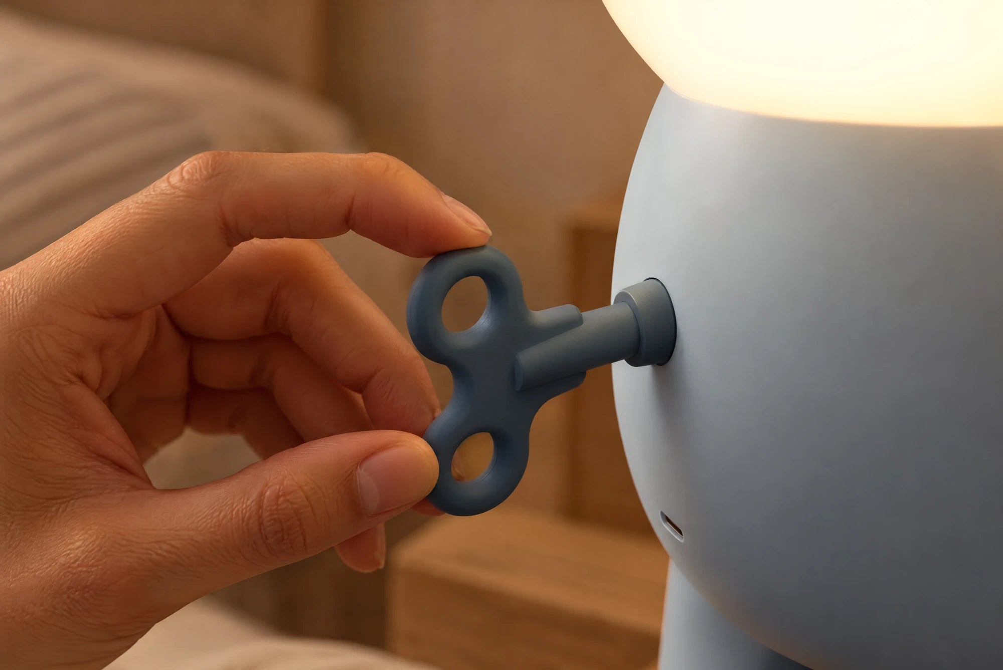 A hand turns Teddy’s blue winding key